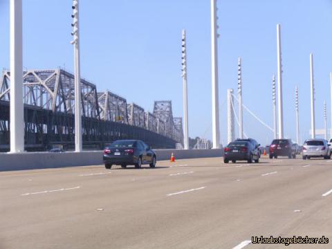 East Bay-Querung: während wir über die gerade neu eröffnete East Bay-Querung der Bay Bridge fahren,
um von Oakland zurück nach San Francisco, Kalifornien zu kommen,
sehen wir nicht nur die neue einhüftige Hängebrücke (auf dem Bild direkt vor uns),
sondern auch noch die alte doppelstöckige Fachwerkbrücke links neben uns,
die aber in den nächsten Jahren abgerissen werden soll