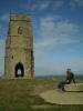 St Michaels: ich (schon wieder sitzend) auf dem Glastonbury Tor
und im Hintergrund die Ruine des Turms von St. Michael’s